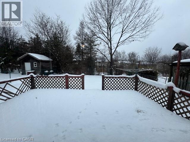A snow-covered landscape with a wooden fence and a small building in the distance.