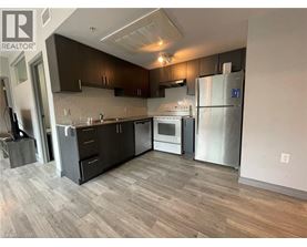 A modern kitchen with dark wood cabinets and stainless steel appliances.