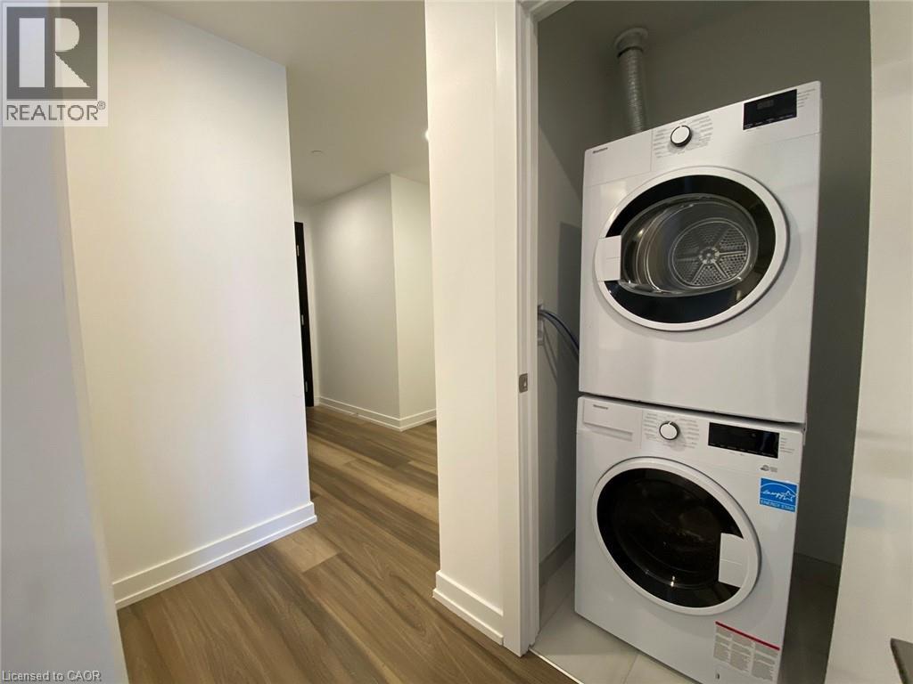 A white washing machine is in a small room with wood flooring.