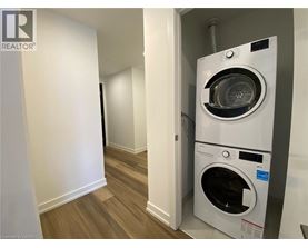 A white washing machine is in a small room with wood flooring.
