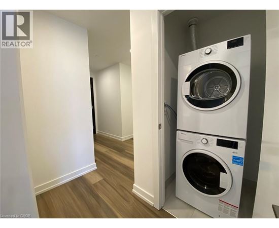 A white washing machine is in a small room with wood flooring.