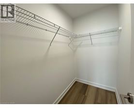 A white wall with a metal rack and a wooden floor.