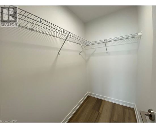 A white wall with a metal rack and a wooden floor.