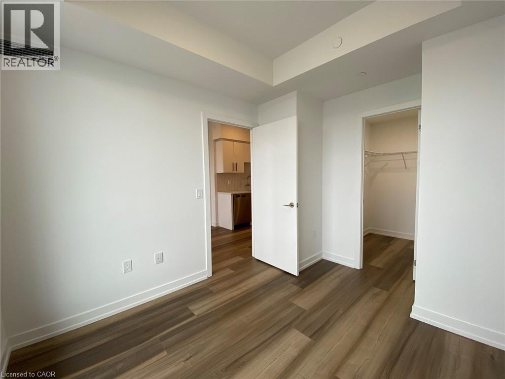 A room with white walls and wood flooring with a doorway leading to another room.