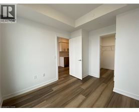 A room with white walls and wood flooring with a doorway leading to another room.
