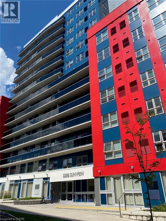 A tall building with a red and blue facade stands next to a smaller building with a white facade.