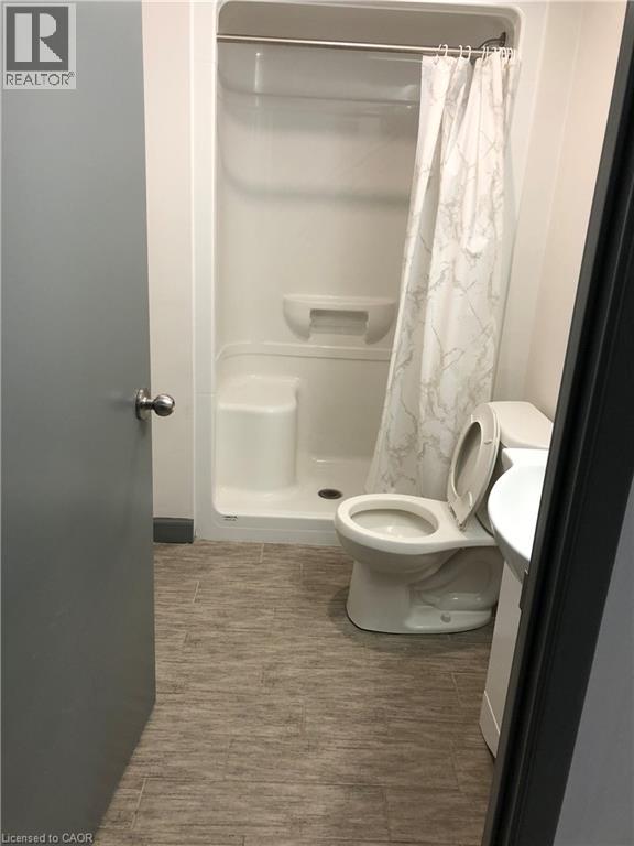 A bathroom with a toilet, a shower stall, and a toilet paper roll.