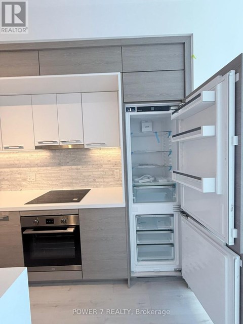 A modern kitchen with a refrigerator that is open to the freezer compartment.