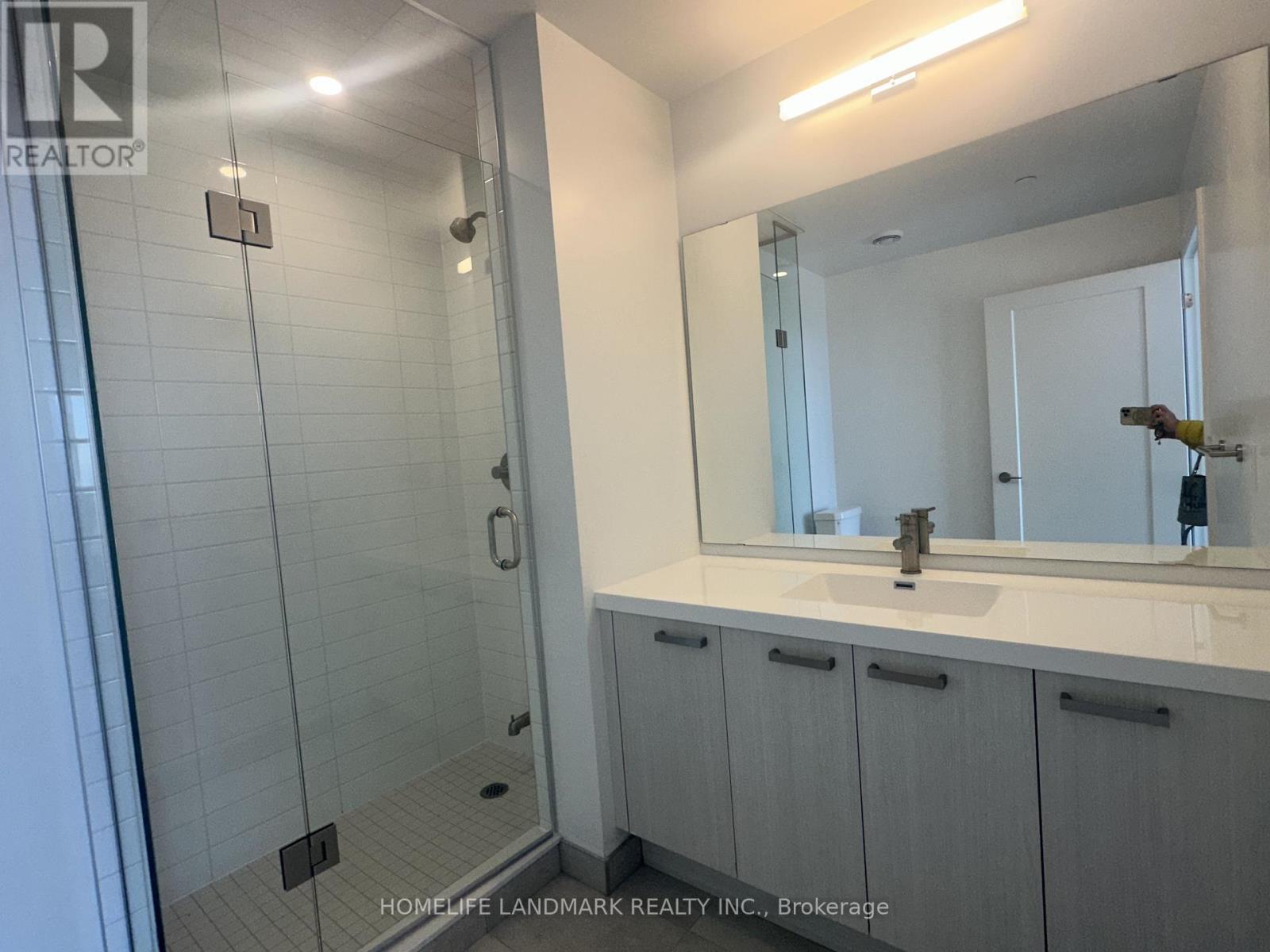 A bathroom with a sink, mirror, and shower.