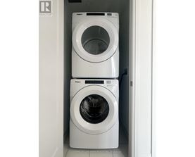 Two white Whirlpool washing machines in a small laundry room.