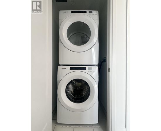 Two white Whirlpool washing machines in a small laundry room.