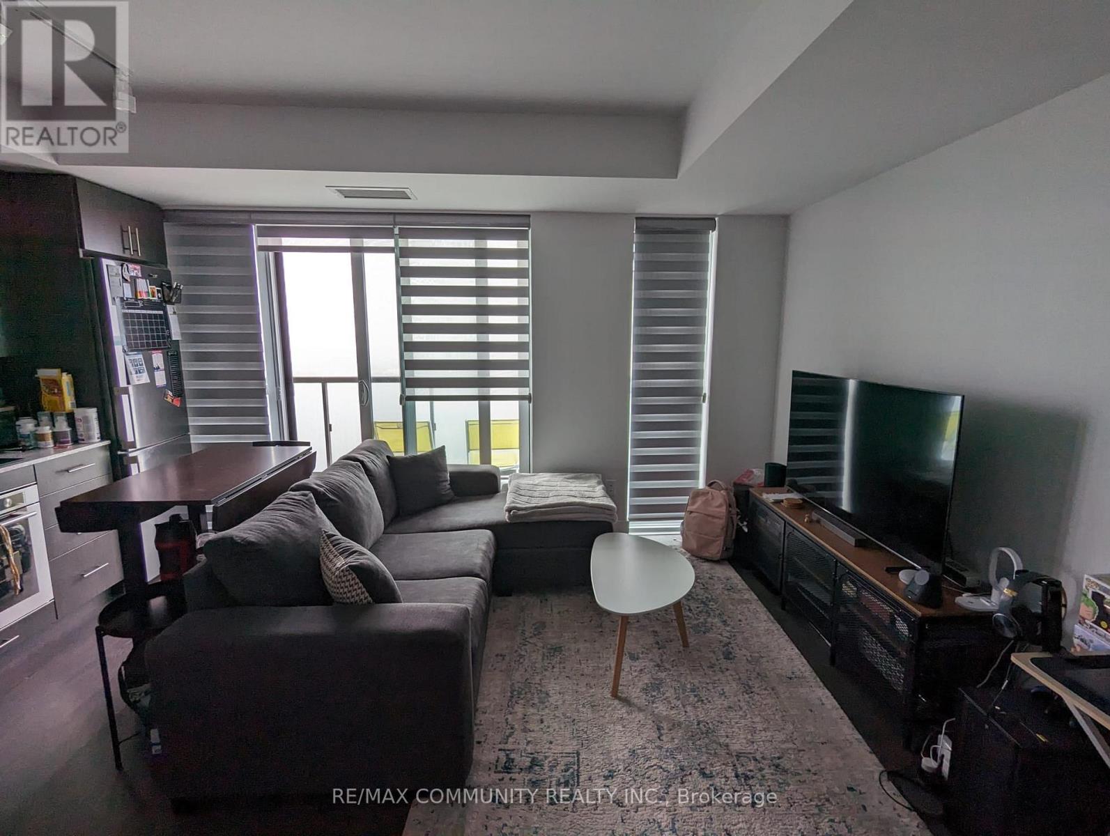 A modern living room with a grey couch, a white table, and a television.