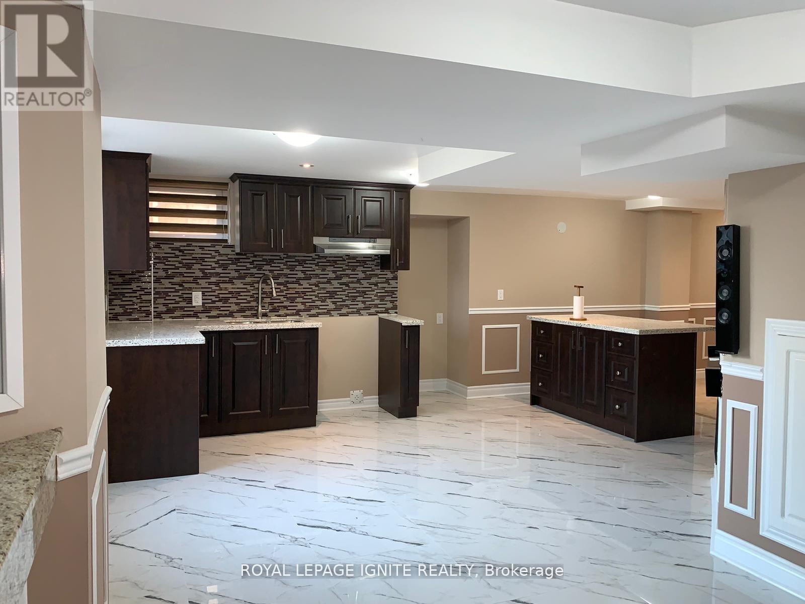 A kitchen with brown cabinets and a marble floor.