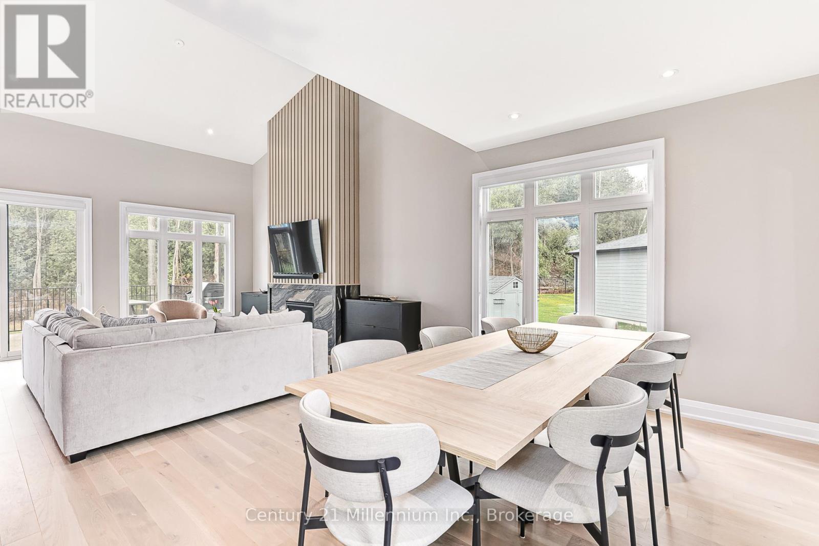 A modern living room with a large grey sofa and a wooden dining table with chairs.