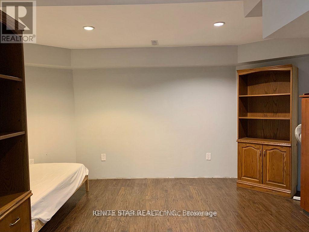 A bedroom with a bed, wooden floor, and a built-in cabinet.