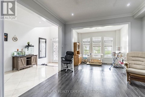 A well-lit, spacious living room with a black leather chair and a beige sofa.