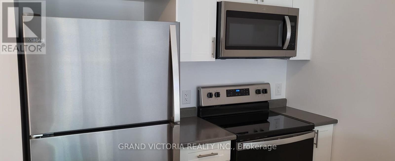 A stainless steel refrigerator is in a kitchen with a black counter top.
