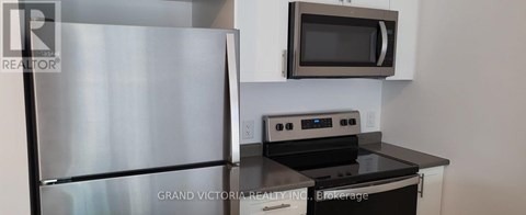 A stainless steel refrigerator is in a kitchen with a black counter top.