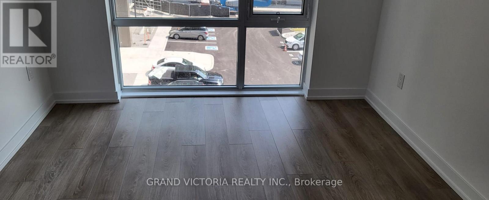 A room with a view of a parking lot through a glass door.