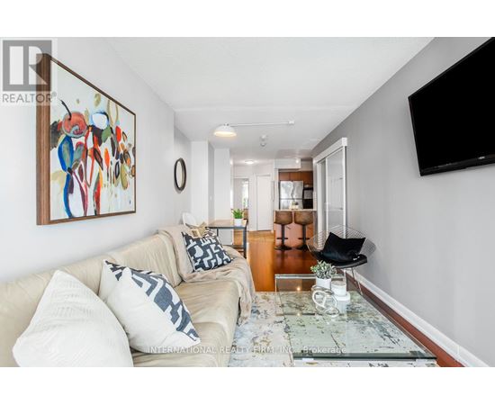 A living room with a couch, a coffee table, and a painting on the wall.