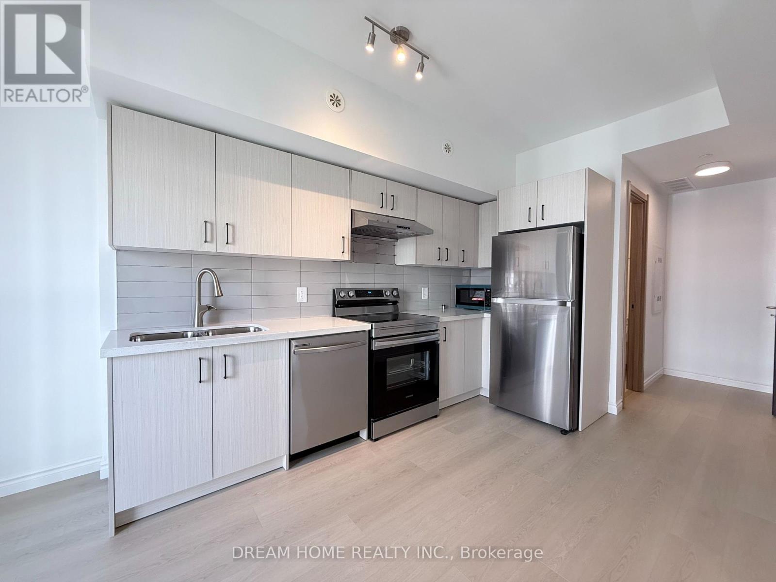 A modern kitchen with white cabinets and stainless steel appliances.