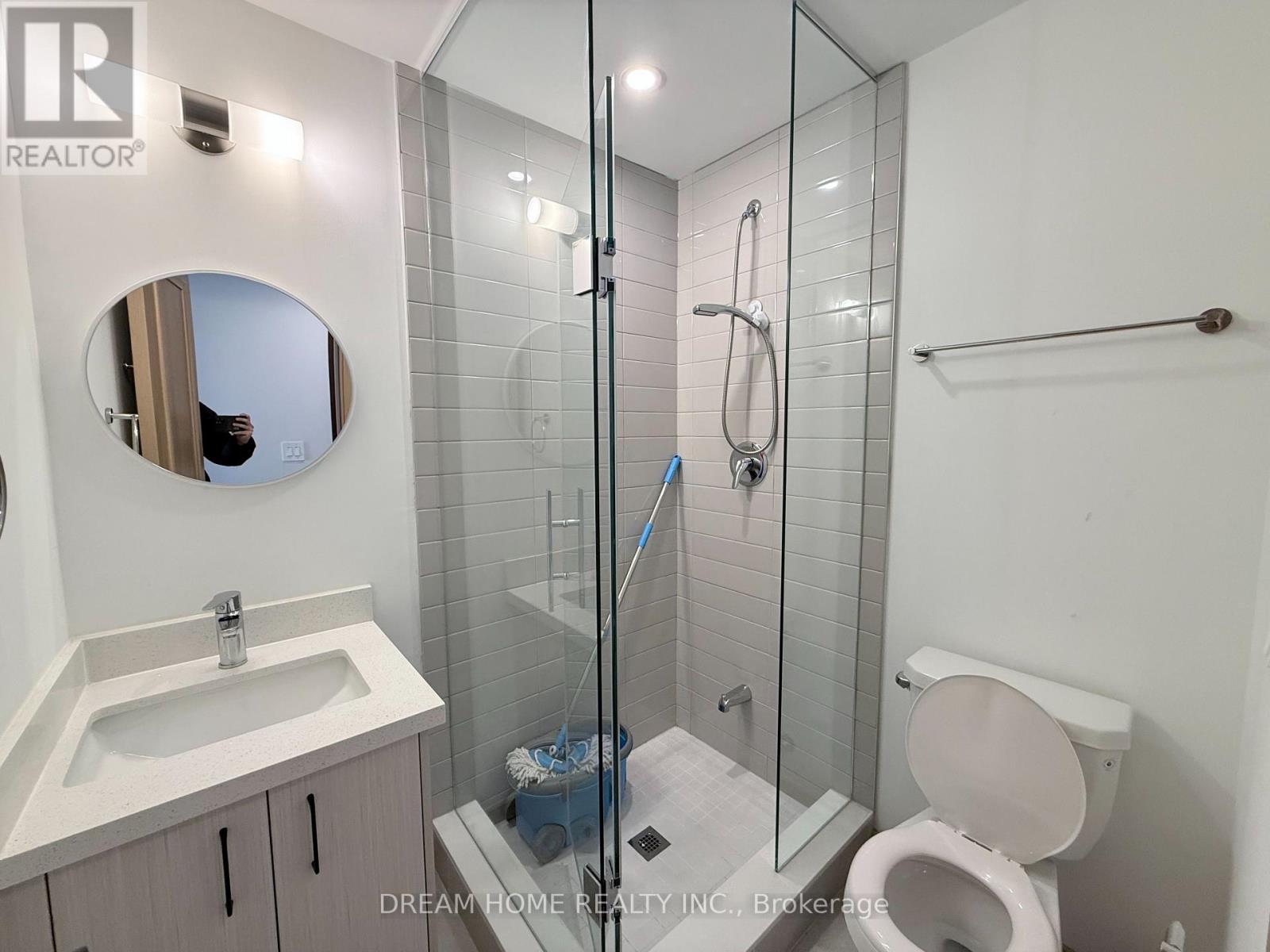 A bathroom with a toilet, sink, mirror, and shower.