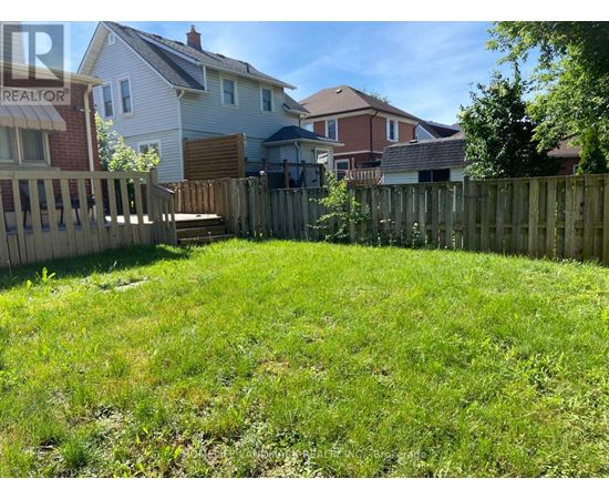 A backyard with a wooden fence and a grassy area.