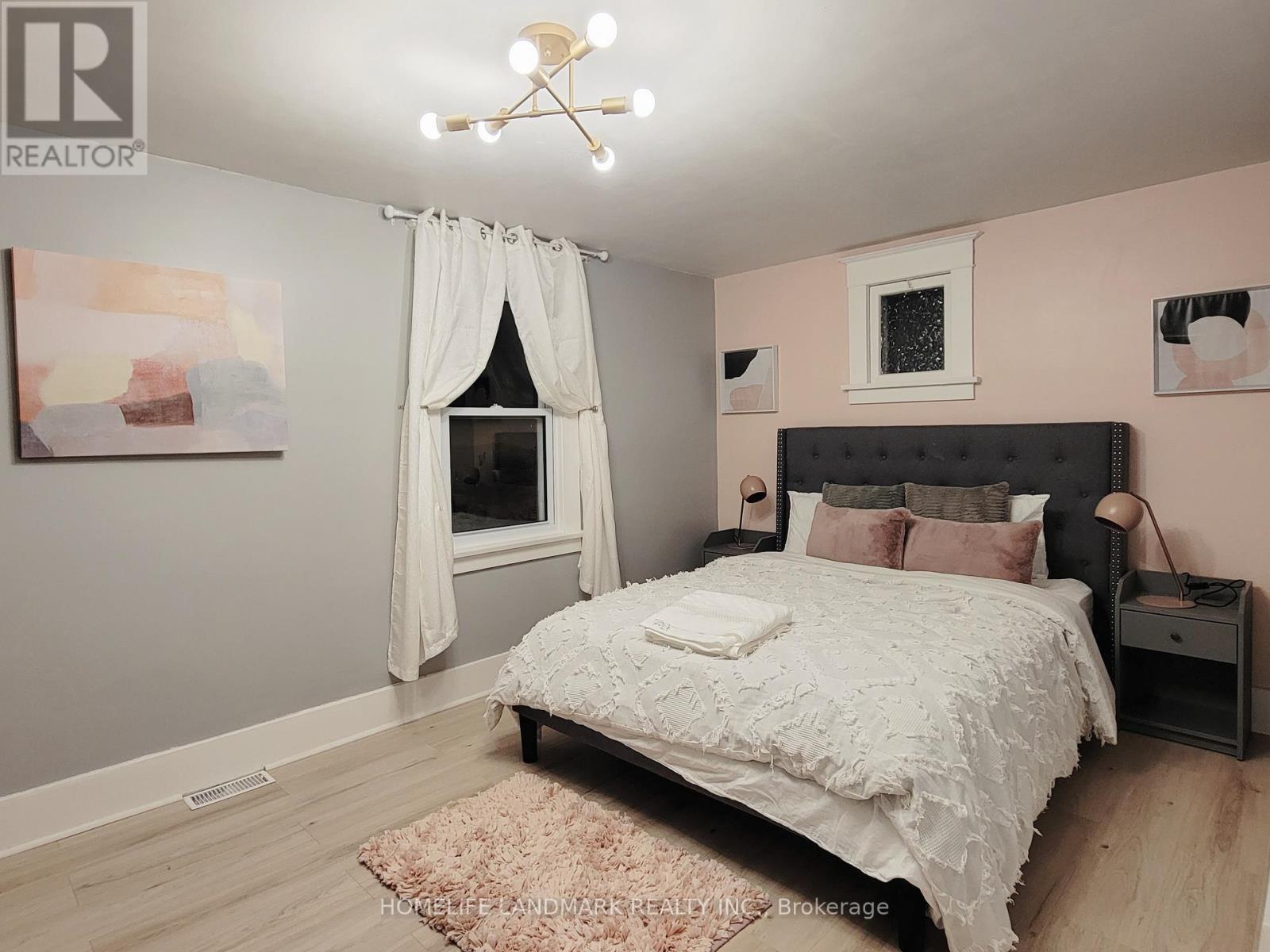 A bedroom with a large bed and a window with curtains.