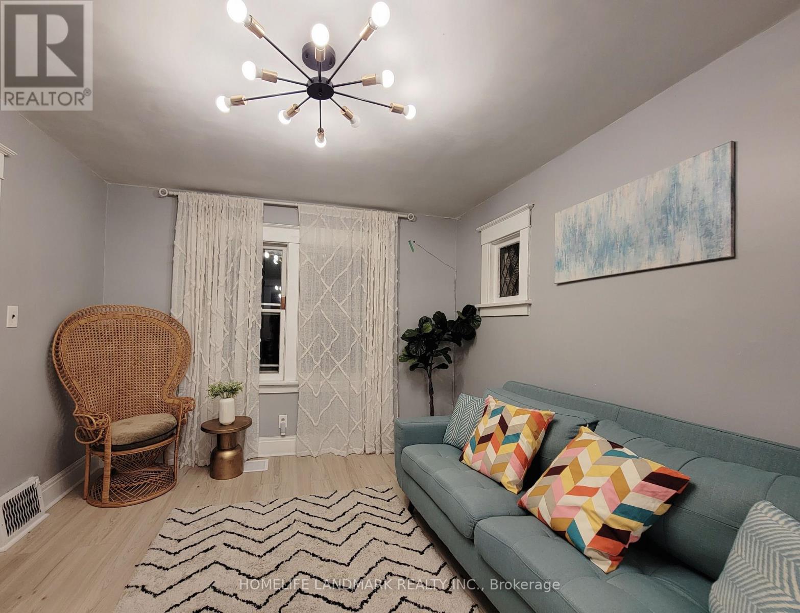 A living room with a couch, chair, and a painting on the wall.