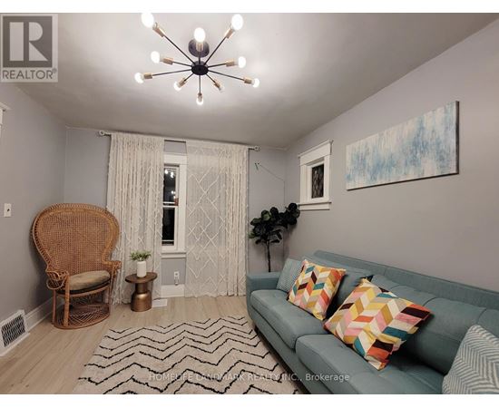 A living room with a couch, chair, and a painting on the wall.