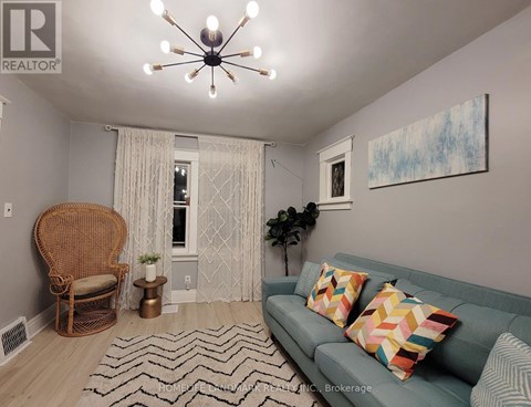 A living room with a couch, chair, and a painting on the wall.