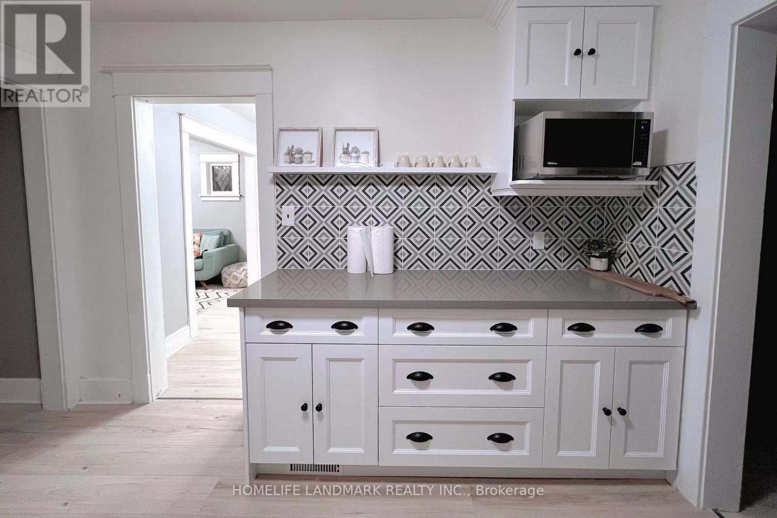 A kitchen with white cabinets and a black and white tiled backsplash.