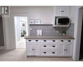 A kitchen with white cabinets and a black and white tiled backsplash.