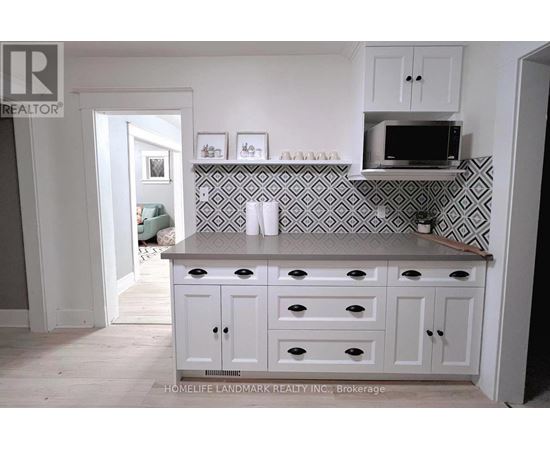 A kitchen with white cabinets and a black and white tiled backsplash.
