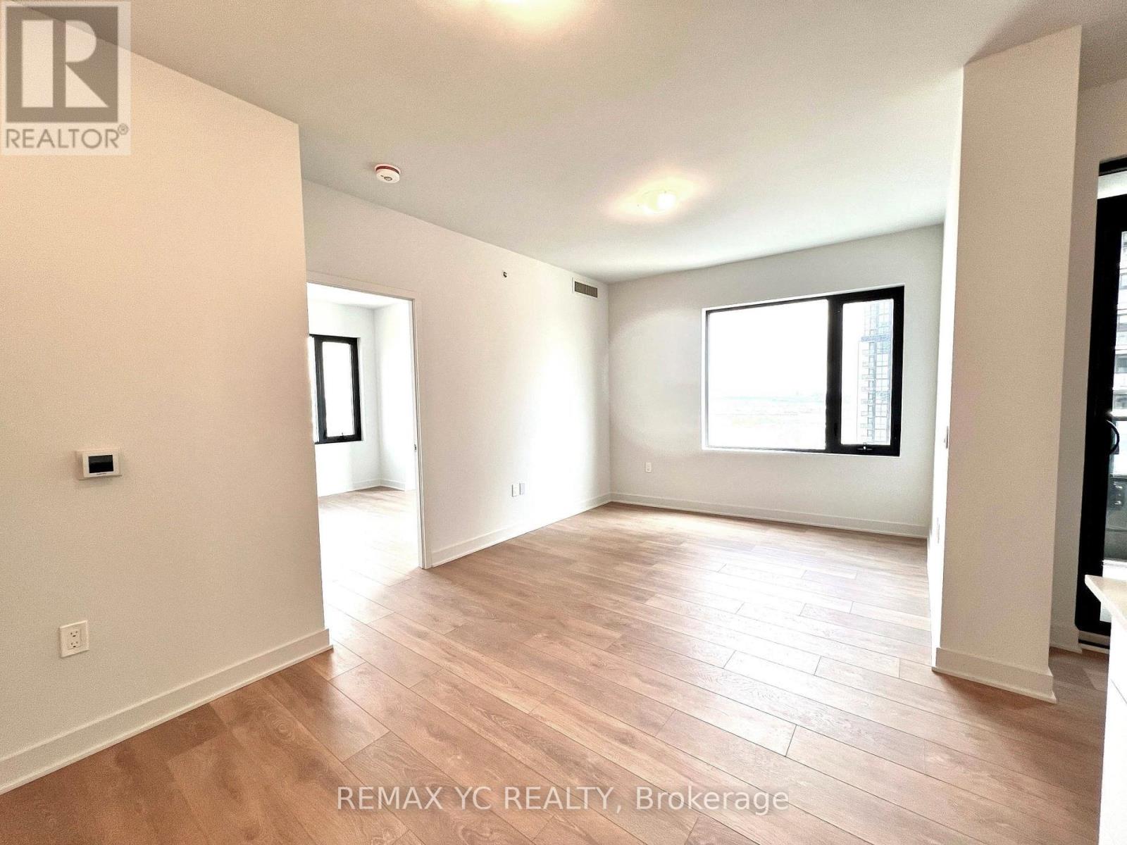 A spacious room with wooden flooring and white walls.