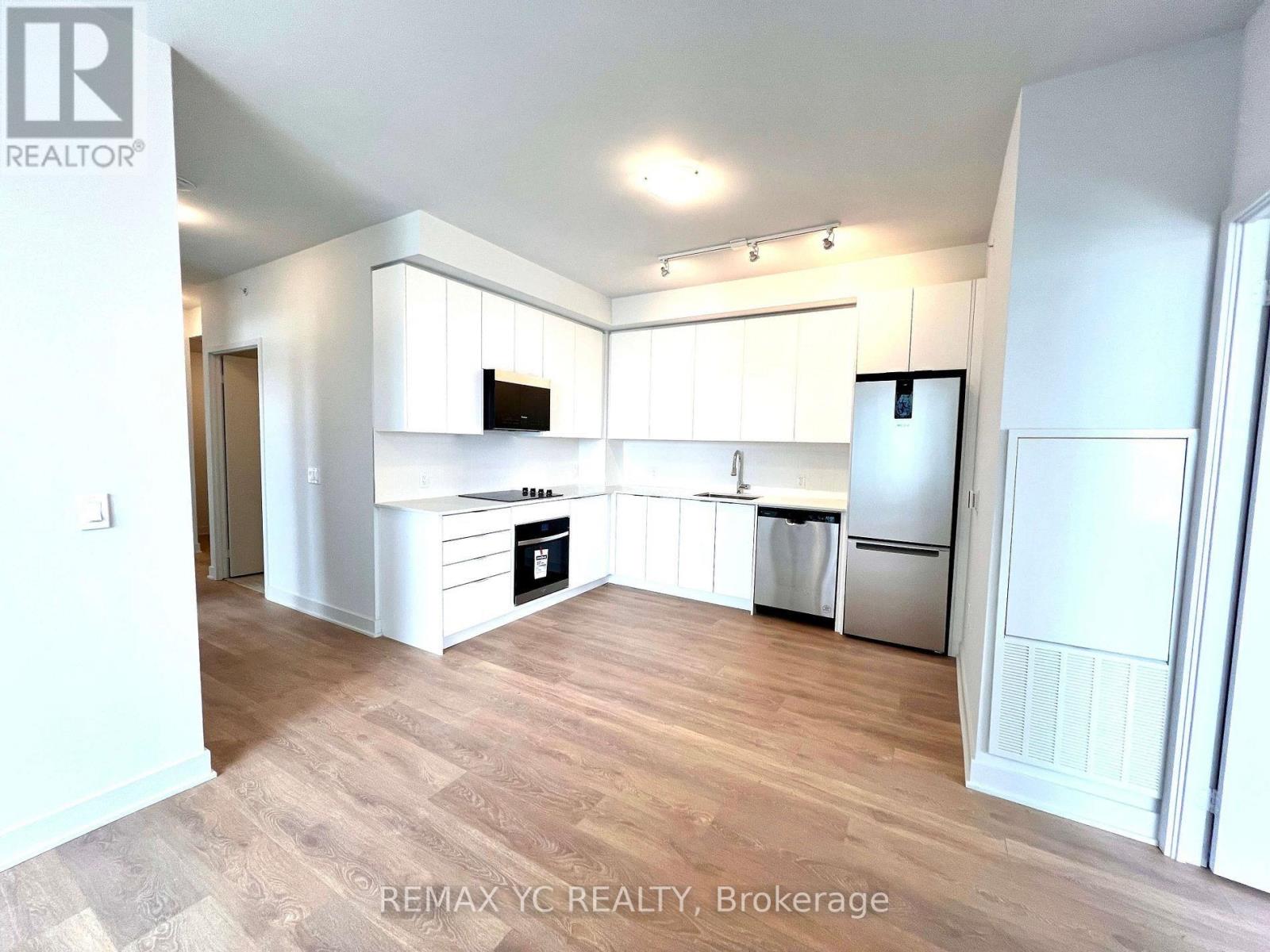 A kitchen with white cabinets and a wooden floor.
