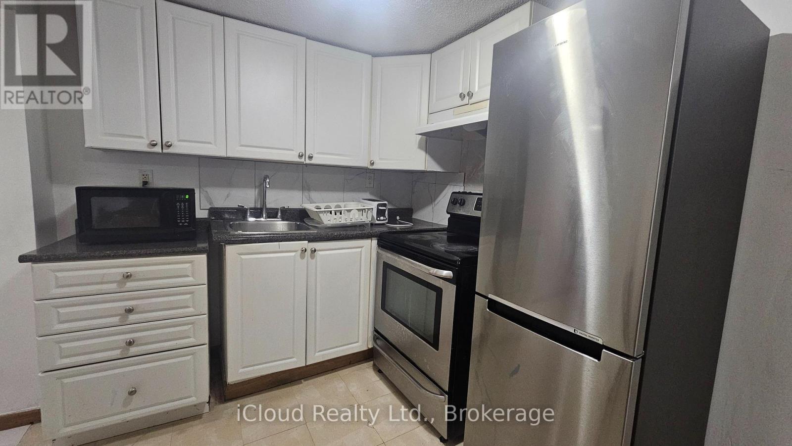 A kitchen with white cabinets and a stainless steel refrigerator.