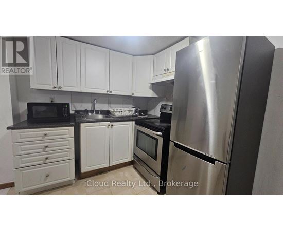 A kitchen with white cabinets and a stainless steel refrigerator.