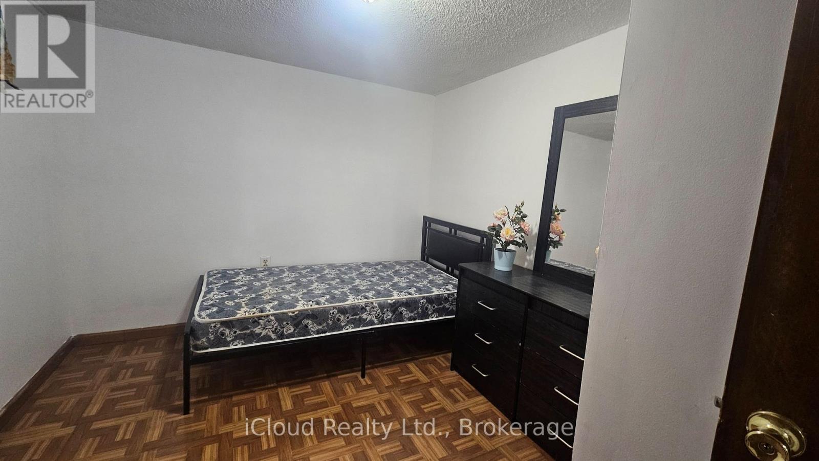 A bedroom with a bed, dresser, and mirror.