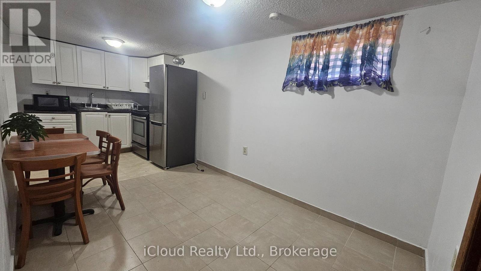 A kitchen with a table and chairs in the foreground and a refrigerator in the background.