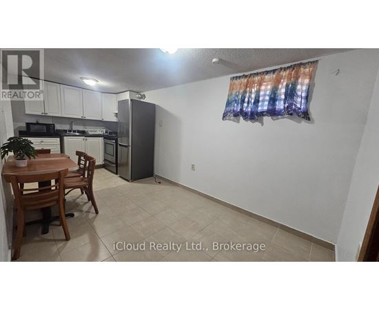 A kitchen with a table and chairs in the foreground and a refrigerator in the background.