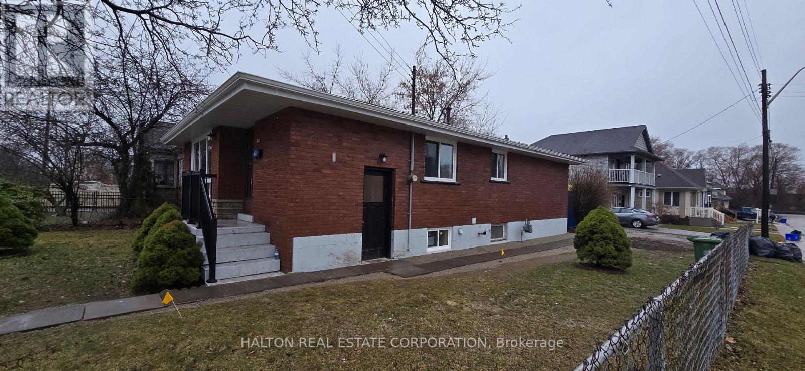 A brick house with a Halton Real Estate Corporation sign in front.