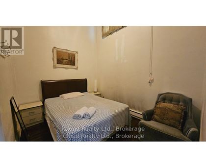 A bedroom with a bed, chair, and a painting on the wall.