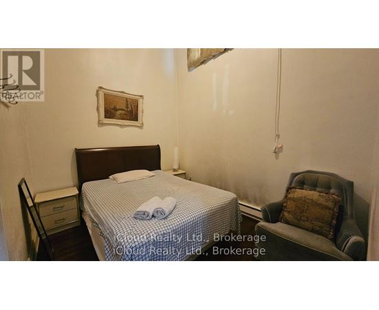 A bedroom with a bed, chair, and a painting on the wall.
