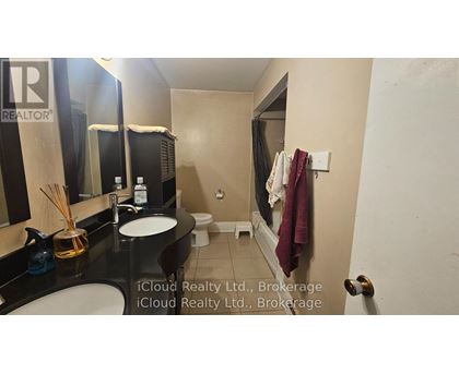 A bathroom with a sink, mirror, toilet, and a towel hanging on the wall.