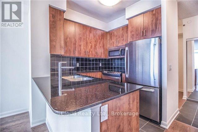A kitchen with wooden cabinets and a stainless steel refrigerator.
