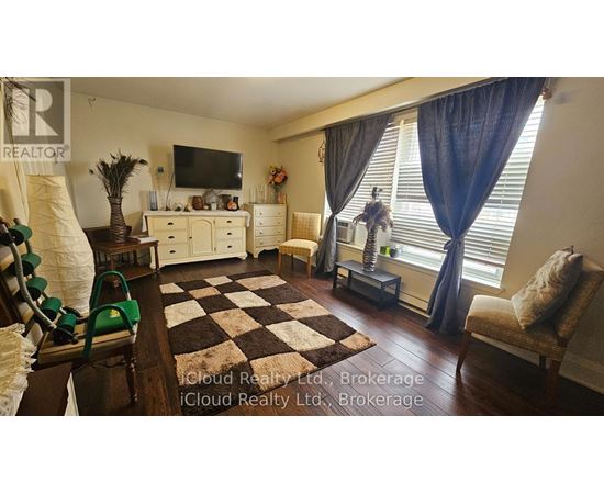 A living room with a checkered rug, a television, and a window with blue curtains.