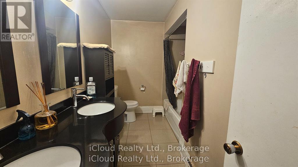 A bathroom with a sink, mirror, toilet, and a towel hanging on the wall.