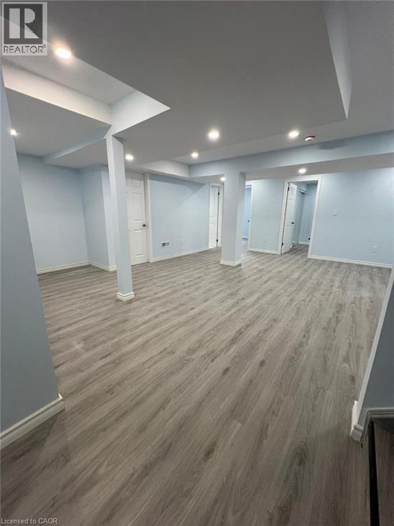 A spacious room with light wood flooring and white walls.