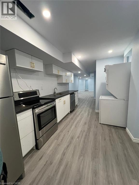 A modern kitchen with white appliances and wood flooring.